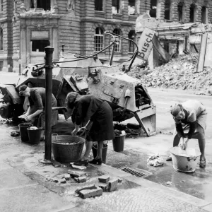 German women doing their washing in cold water in a street beside a knocked out German German women doing their washing in cold water in a street beside a knocked out German
