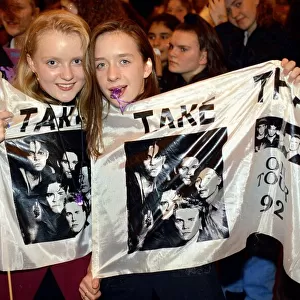 Girl fans of pop group take That holding a flag with the group