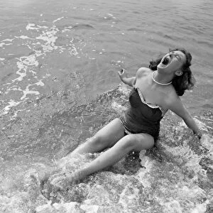 A girl screams out as she sits down in the cold water during a visit to the beach in