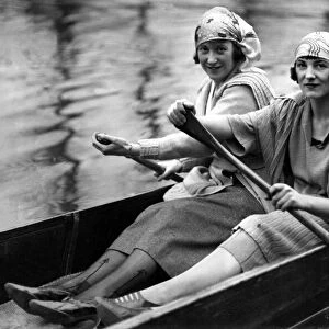 Two girls rowing a boat in a London park as the sun comes out, May 1945