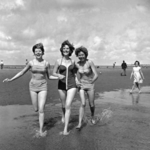 Girls in swimsuits running on the beach at Blackpool. 5th August 1958