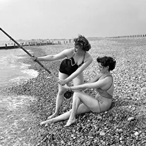 Two girls try a spot of fishing during a visit to the beach in Springtime Britain