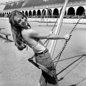 Glamour model in striped vest top and jeans on a playground swing Print Glamour model in striped vest top and jeans on a playground swing Print