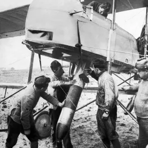 Ground crew fit the tail vanes and manoeuvre a bomb into the bomb bay of a French Air