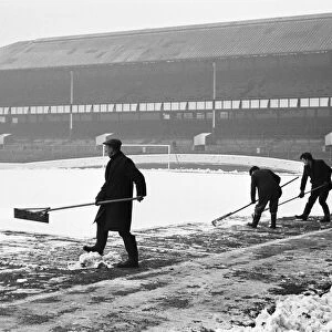 Groundsmen try to clear the snow from the pitch at Goodison Park