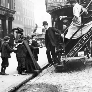 A group of children ask a male bus passenger for hisused ticket as he descends from