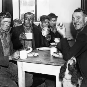 Un groupe de mineurs se prélassant à un repas après l'ouverture d'une cantine du tènement à la carrière Isabella.