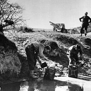 Gunners fill up their cans at a desert water-hole, had their first wash for days