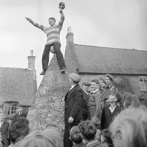 Hallaton Barrel Kicking man perched atop of a stone structure circa 1946