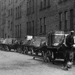 Heavy horses with their carts wait to offload their deliveries in this un-named