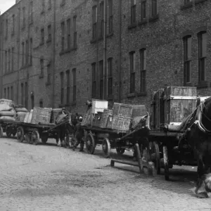 Heavy horses with their carts wait to offload their deliveries in this un-named Heavy horses with their carts wait to offload their deliveries in this un-named