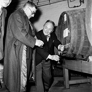 Hector Hughes, Q. C. pours out a glass of sherry out of one of the large barrels for one
