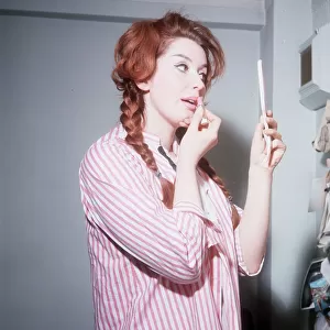 Heller Toren model actress 1964 puting on lipstick holding hand mirror pink striped shirt