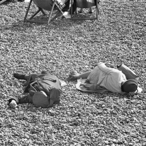 Holiday scenes at Brighton. Two elderly holidaymakers sleeping on the beach after Holiday scenes at Brighton. Two elderly holidaymakers sleeping on the beach after