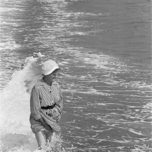 Holiday scenes at Brighton Elderly woman paddling in the sea holding her skirt up Holiday scenes at Brighton Elderly woman paddling in the sea holding her skirt up