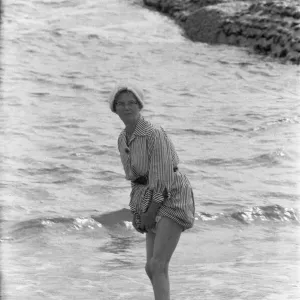 Holiday scenes at Brighton Elderly women paddling on the beach holding her skirt Holiday scenes at Brighton Elderly women paddling on the beach holding her skirt