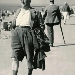 A holidaymaker with his raincoat under his arm strolls along the seafront at Clacton A holidaymaker with his raincoat under his arm strolls along the seafront at Clacton