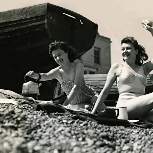 Holidaymakers boil a kettle to make a cup a tea on the pebble beach June 1945