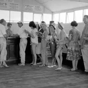 Holidaymakers line up to make a bet at a betting shop in the form of a wooden chalet
