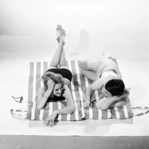 Holidays: Man and Woman demonstrating the beach bag that converts into a beach mat