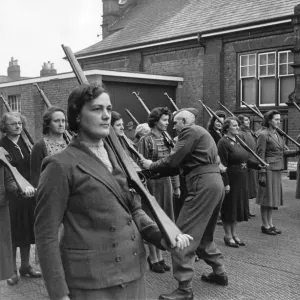 A Home Guard Sergeant giving women instructions on holding rifles during a drill A Home Guard Sergeant giving women instructions on holding rifles during a drill