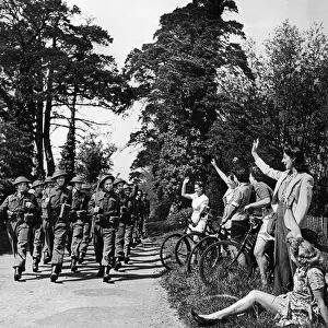 Home Guard volunteers are cheered by local residents sitting on the side of the road as