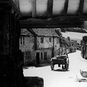 Horse drawn cart makes its way down a typical Cotswold village road in Gloucestershire