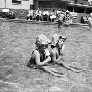 Hot weather scenes in Margate, Kent. Two young girls eating ice lollies while sitting in Hot weather scenes in Margate, Kent. Two young girls eating ice lollies while sitting in