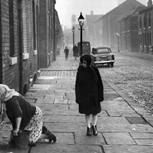 A housewife stoning the steps in Nelson Street, Manchester. 1st December 1961