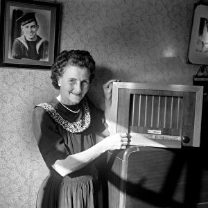 A housewife tunes in her wireless set to The BBC home service. Circa 1953 D6046