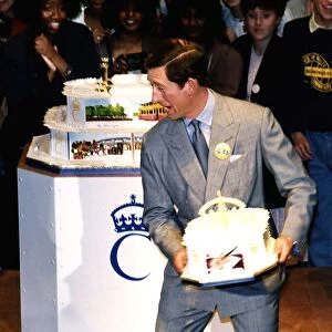 HRH Prince Charles about to throw a birthday cake to a crowd of onlookers during his