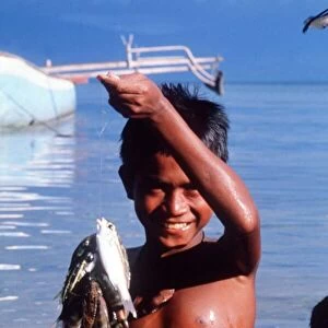Indonesia young boy fishing and showing off his catch Circa 1985
