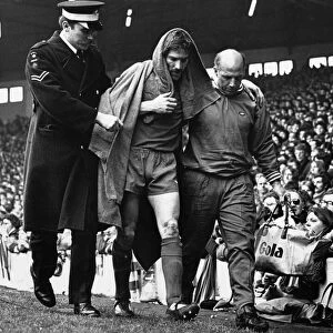 Injured Liverpool footballer Steve Heighway is helped off the pitch by trainer Ronnie