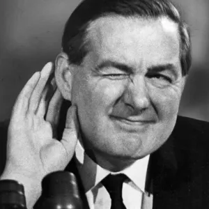 Print of James Callaghan in mock listening pose at a 1964 press conference