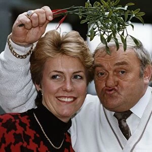 Jill Dando TV Presenter with Les Dawson who is holding mistletoe over their heads