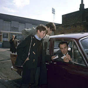 Jimmy Greaves of Tottenham Hotspur signs autographs for young fans as he leaves White