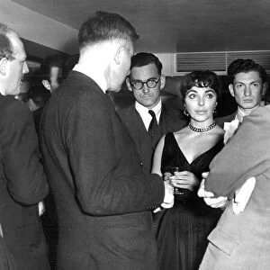 Joan Collins among crowd of reporters at press event at the Savoy Hotel - October 1955