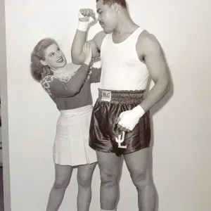 Joe Louis con modelo femenina cheerleader sintiendo el tamaño de su bíceps en Earls Court. Joe Louis con modelo femenina cheerleader sintiendo el tamaño de su bíceps en Earls Court.