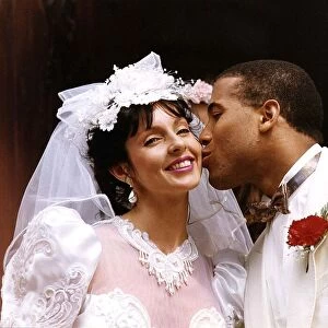 John Barnes and his bride Suz, both dressed in white, share a kiss after their wedding