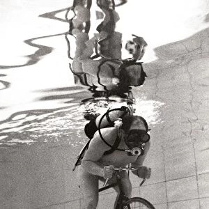 John Camm rides bicycle underwater at his local swimming pool with the aid of an