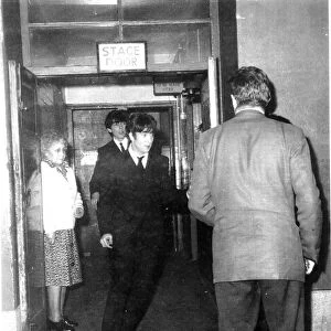 John Lennon and George Harrison make their way through the stage door after