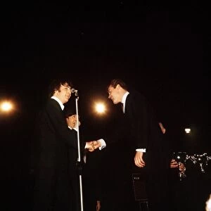 John Lennon and Paul McCartney of The Beatles receiving awards from Roger Moore at