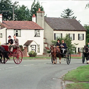 Judges in horse-drawn carriages view the village of Hartlebury, Worcestershire