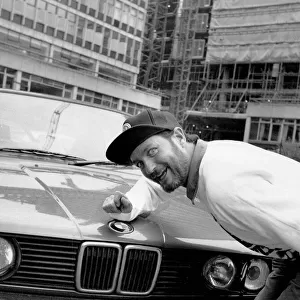 Kenny Everett sitting with his new BMW car 21 / 07 / 1989