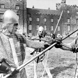 Knaves in jerkins and steel helmets battle with quarter staffs during the jousting at