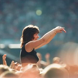 A lady aloft and enjoying the day, part of the huge audience watch American Rock Group
