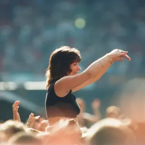 A lady aloft and enjoying the day, part of the huge audience watch American Rock Group A lady aloft and enjoying the day, part of the huge audience watch American Rock Group