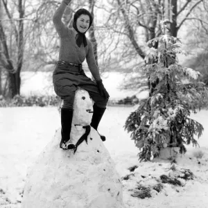 A land army girl in Sussex sitting on top of her Hitler snowman during the Second World A land army girl in Sussex sitting on top of her Hitler snowman during the Second World
