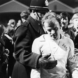 Leeds captain Billy Bremner leaves the field on the consoling arm of the law after his