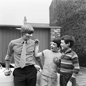 Liverpool footballer Alun Evans speaks to two young fans who inspect his damaged eye as